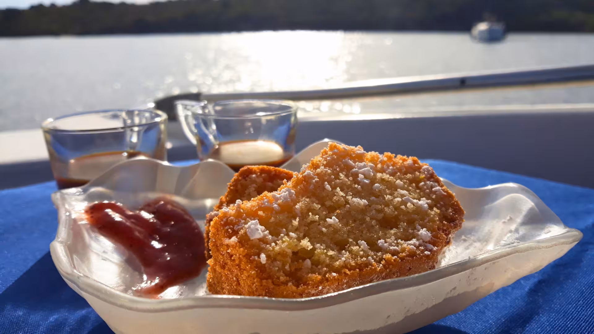 Close-up of a dessert with jam and coffee on a boat, capturing the serene backdrop of a La Maddalena boat tour.