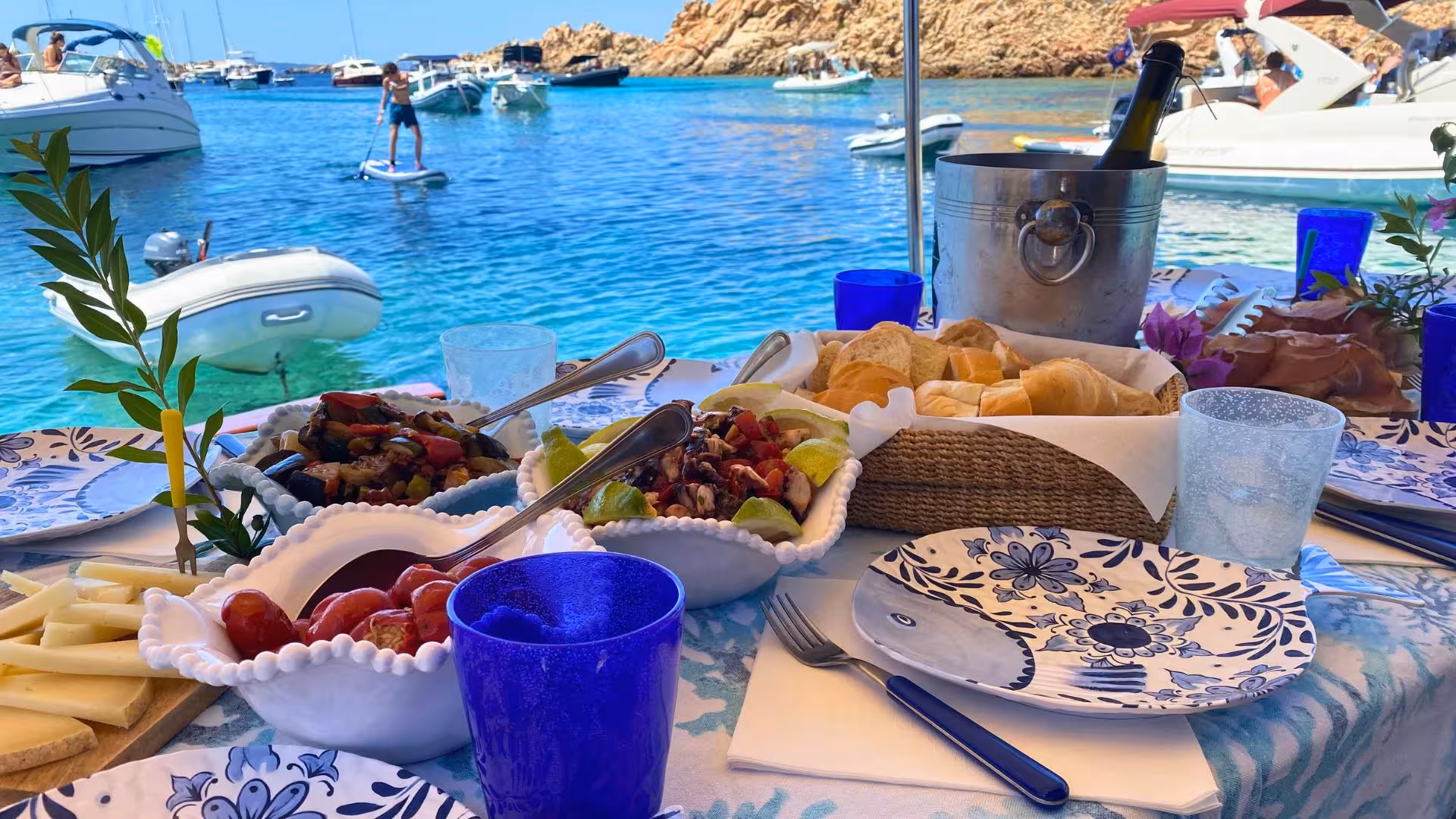 Gourmet lunch spread on a boat in La Maddalena, featuring fresh seafood and vibrant tableware, with stunning sea views.