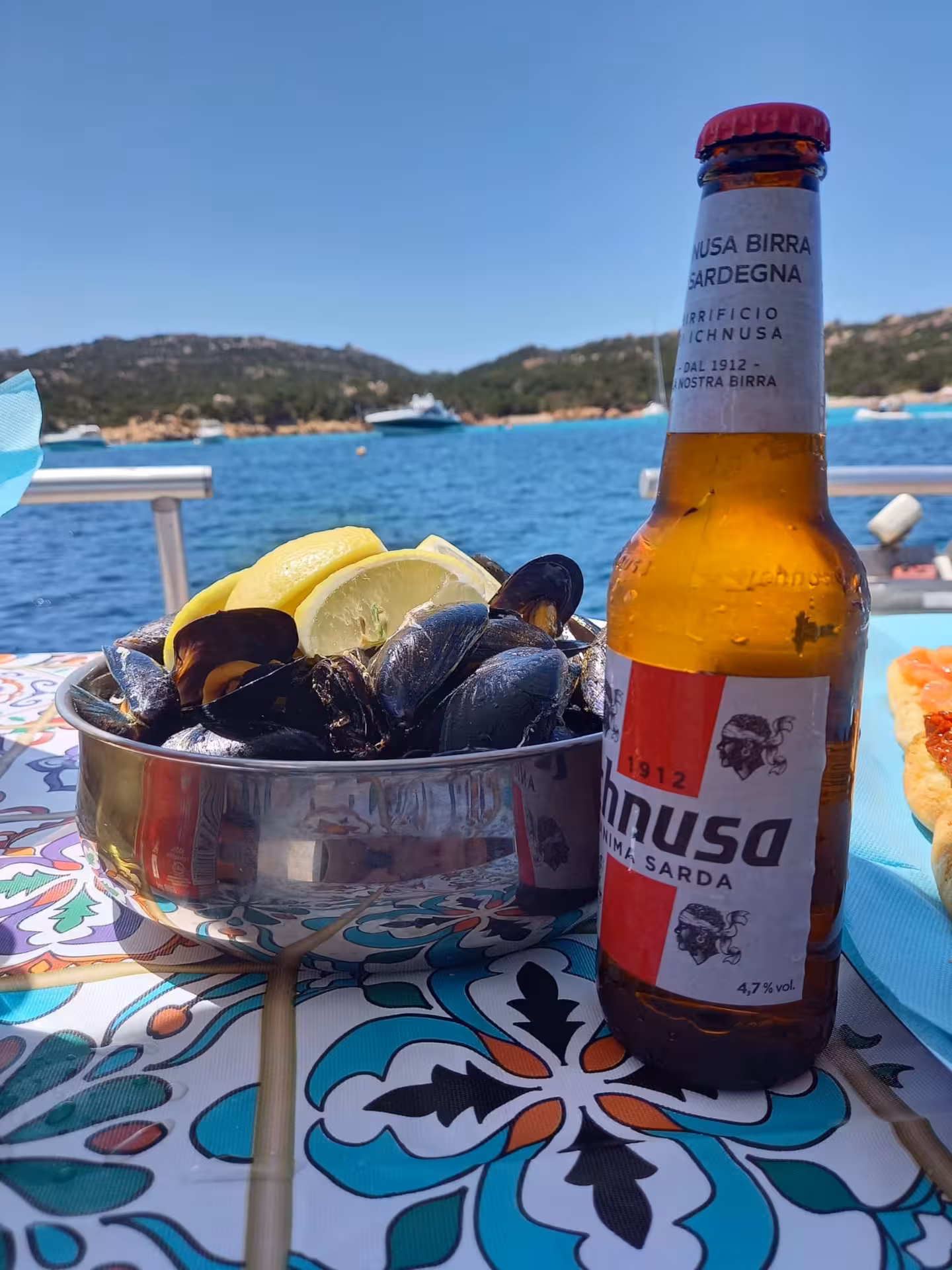 Enjoy fresh mussels with lemon and local beer against the stunning backdrop of the La Maddalena Archipelago.
