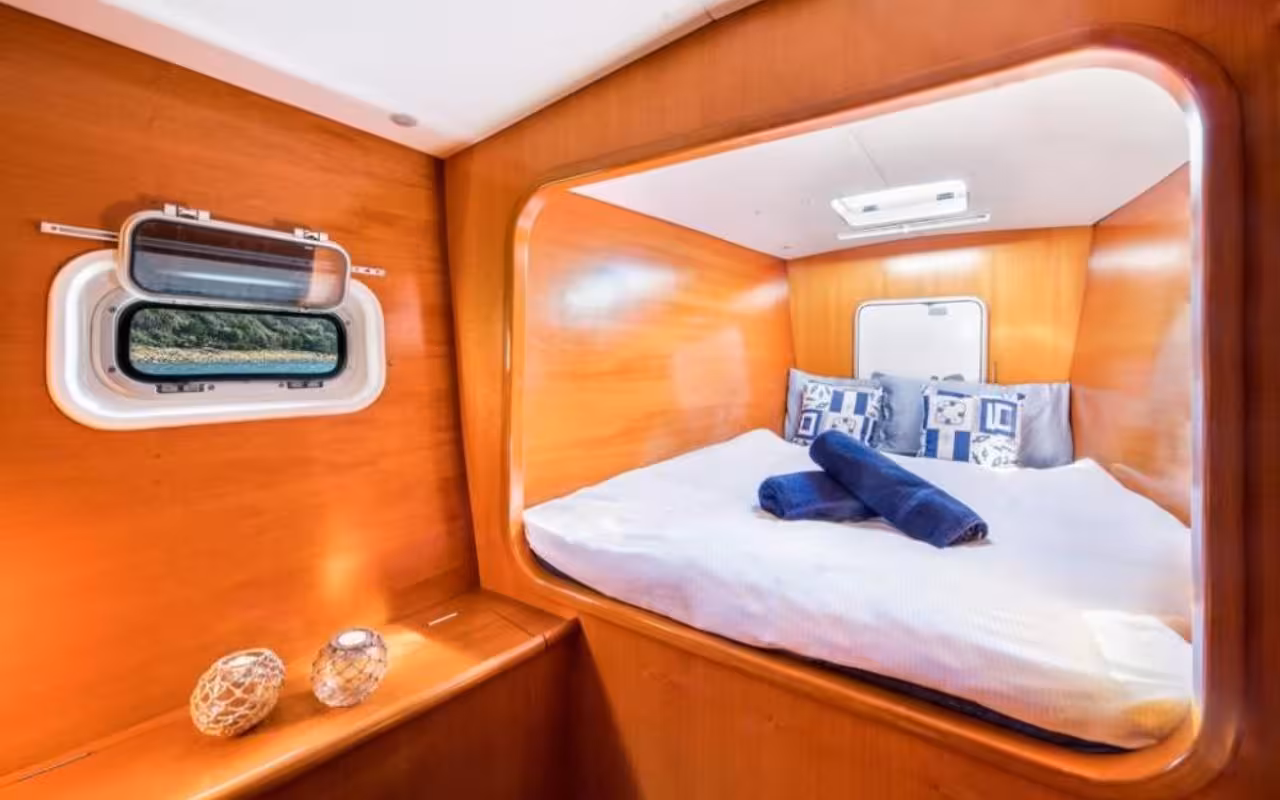 Comfortable cabin with a scenic view window, perfect for relaxation on a La Maddalena Archipelago catamaran tour.