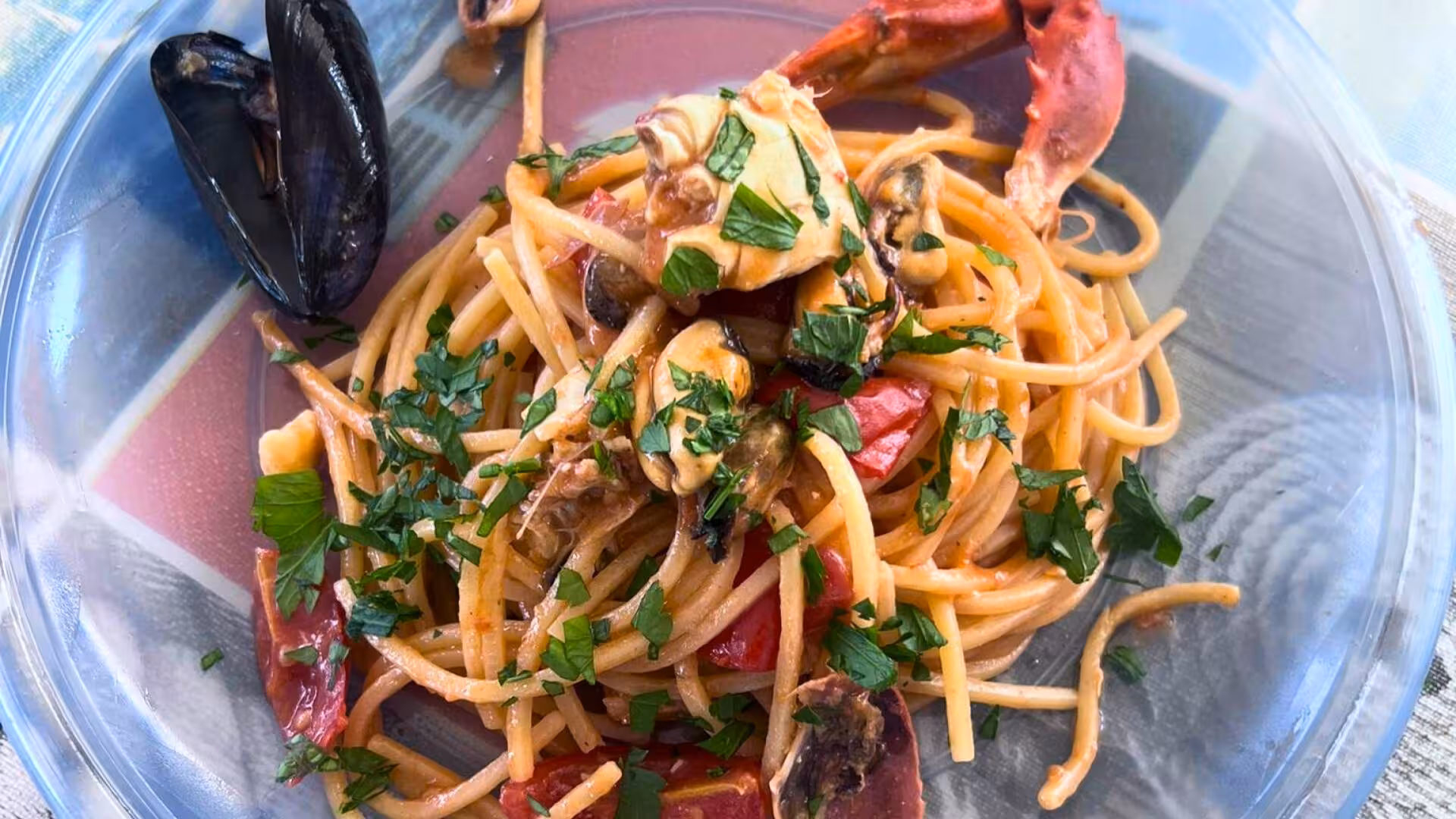 Savor fresh seafood pasta with mussels and crab, garnished with parsley on the La Maddalena catamaran tour.