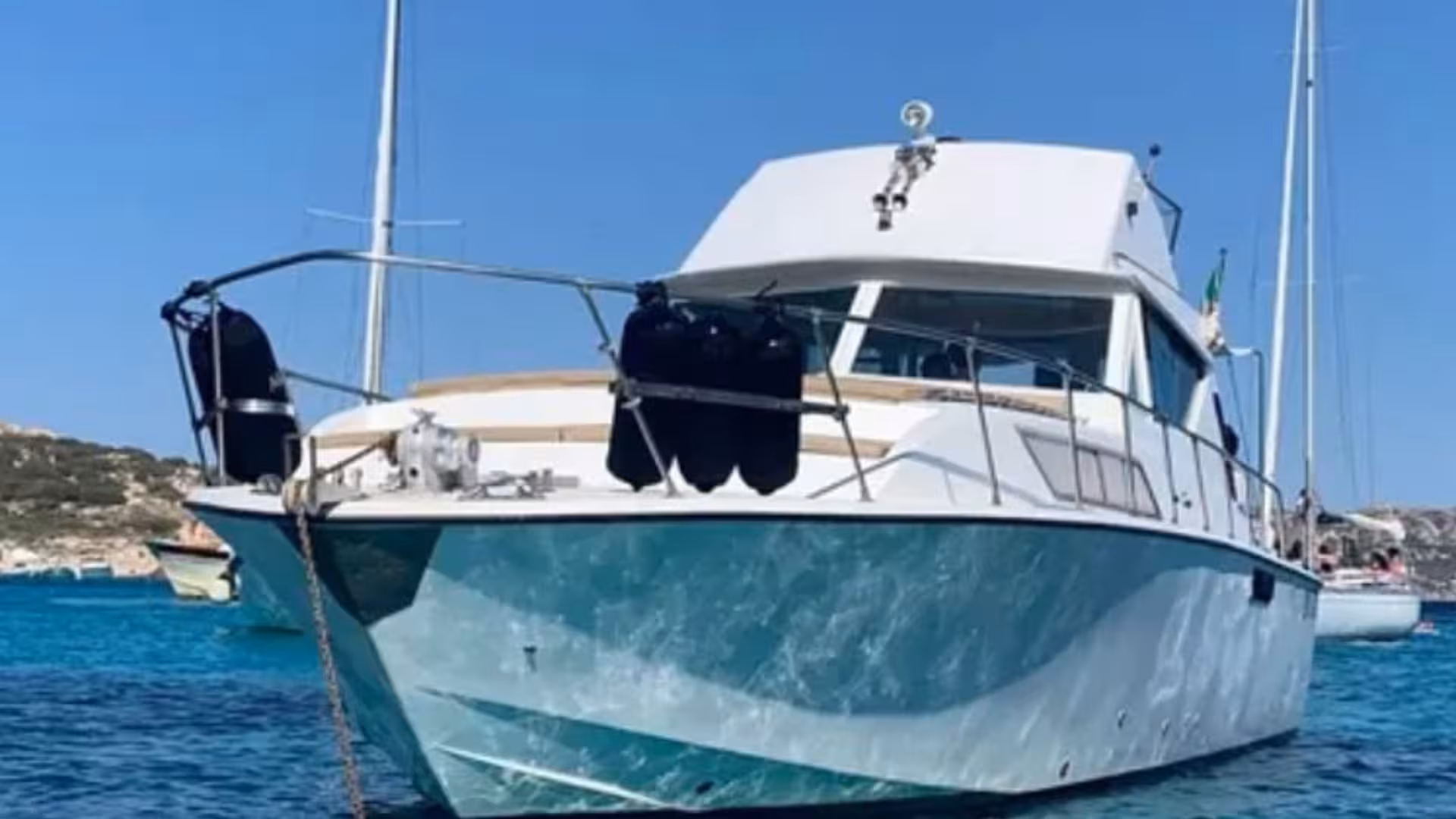 Close-up of a sleek tour boat anchored in the crystal-clear waters of La Maddalena, offering a luxurious boat tour experience.