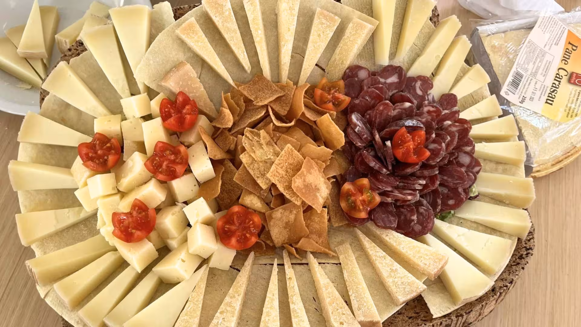 Assorted cheese and salami platter with pane carasau and cherry tomatoes, perfect for a La Maddalena Archipelago picnic.