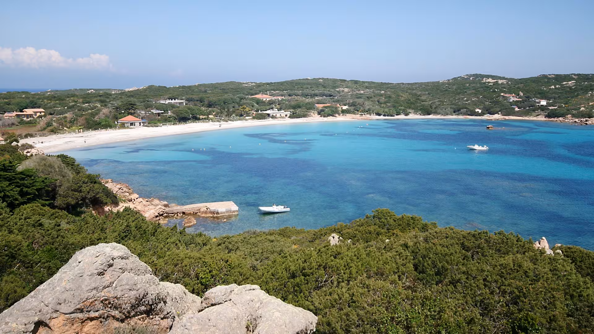 Aerial view of a serene beach and clear blue waters near La Maddalena, ideal for a private dinghy tour.