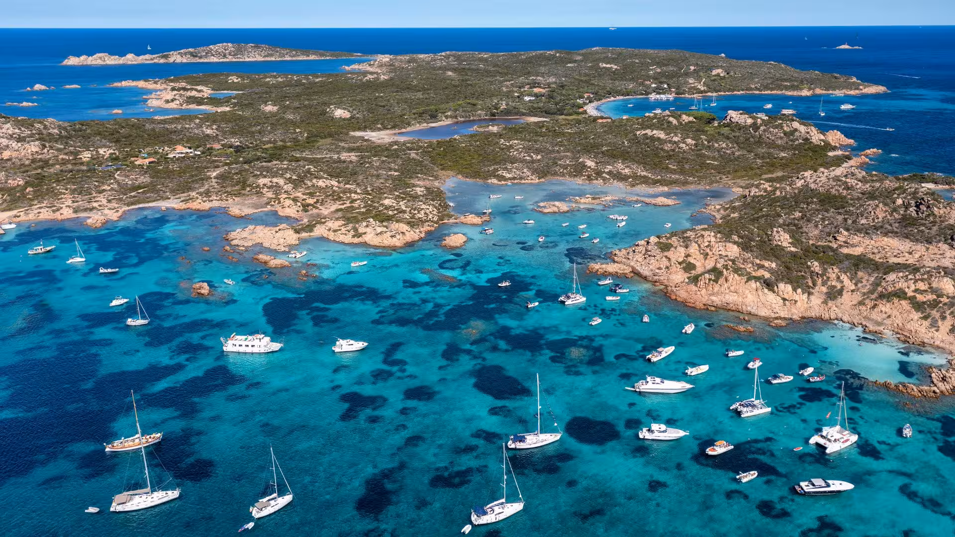 Aerial view of boats anchored in the turquoise waters of La Maddalena Archipelago, ideal for private dinghy tours.