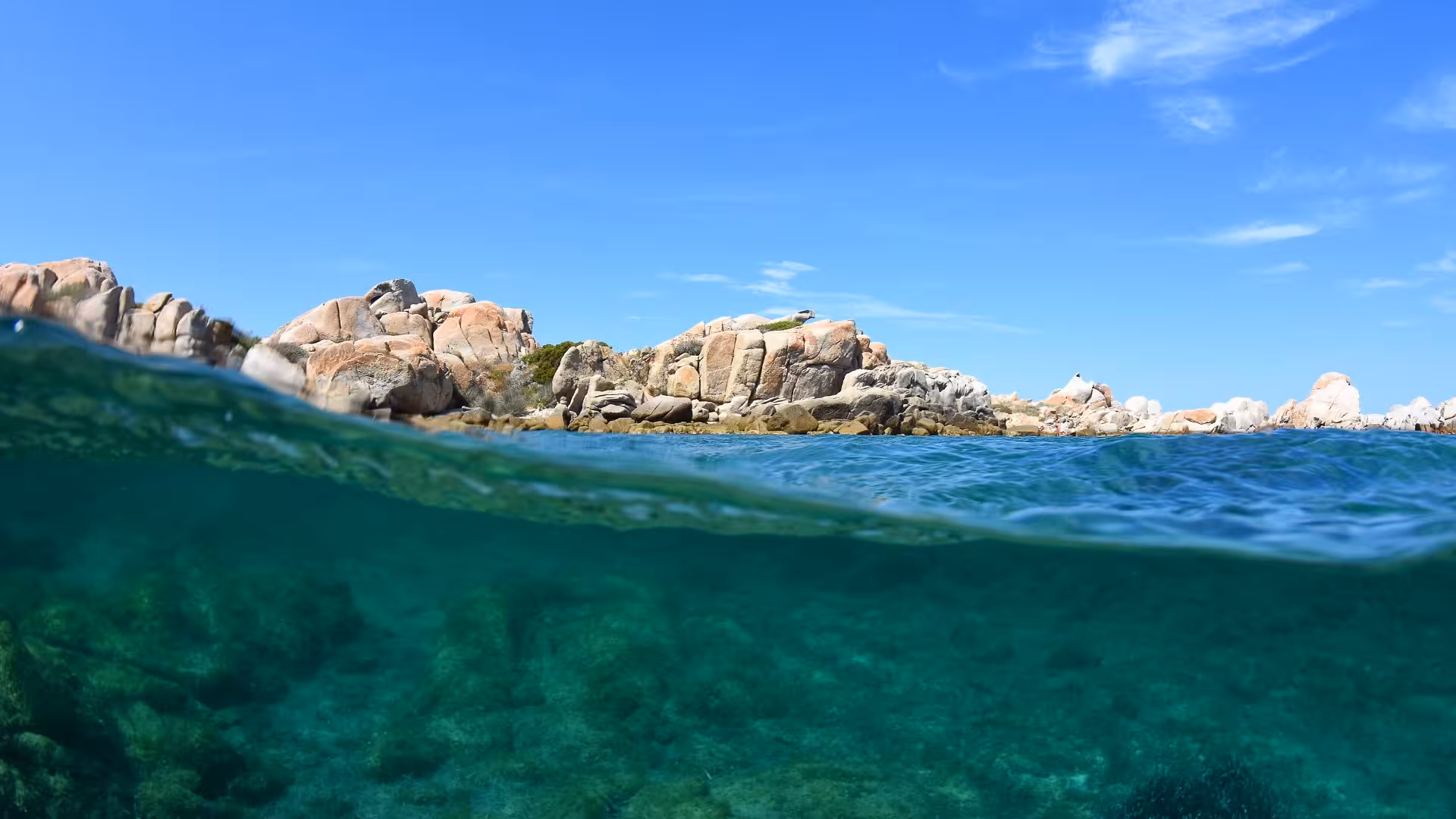 Scenic view of rocky coastline and crystal-clear waters in La Maddalena, ideal for wooden boat tours in Corsica.