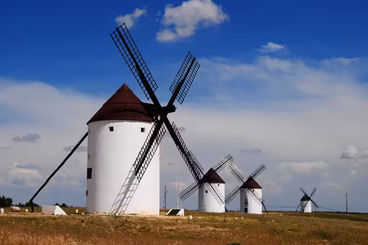 Traditional La Mancha windmills under blue sky, iconic scenery featured on the Don Quixote Tour Spain