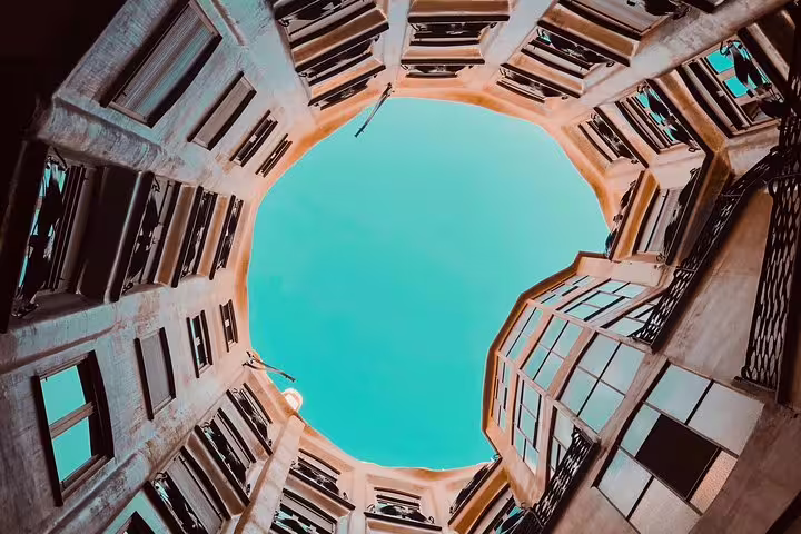Looking up at the courtyard of La Pedrera, revealing Gaudi's innovative design and open sky view.