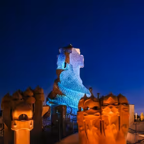 La Pedrera Night Experience rooftop in Barcelona, Gaudí chimneys lit under deep blue evening sky
