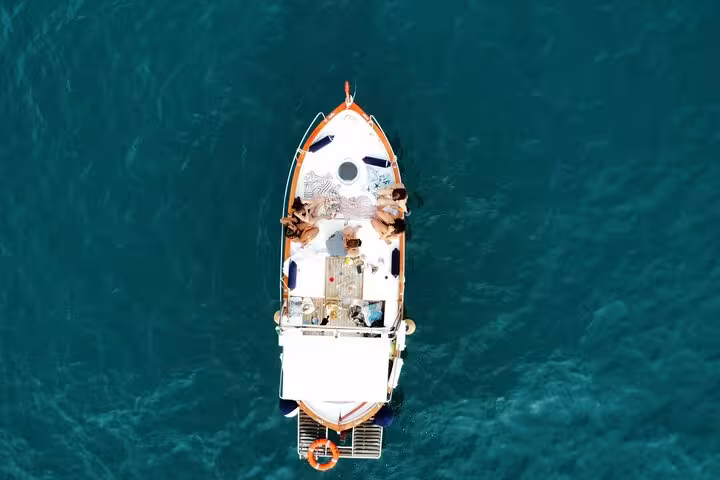 Aerial view of a small boat with passengers relaxing on a turquoise sea during the La Spezia boat tour.