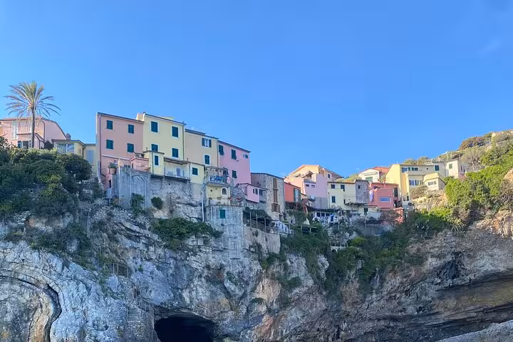 Colorful hillside houses perched on rocky cliffs under a clear blue sky in the 3 Islands tour from La Spezia.