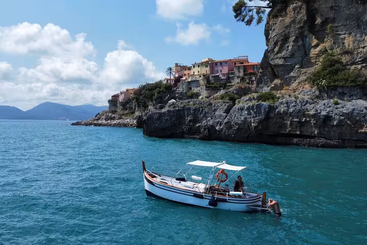 A scenic boat sails near rocky cliffs and colorful houses near Lerici on the La Spezia boat tour.