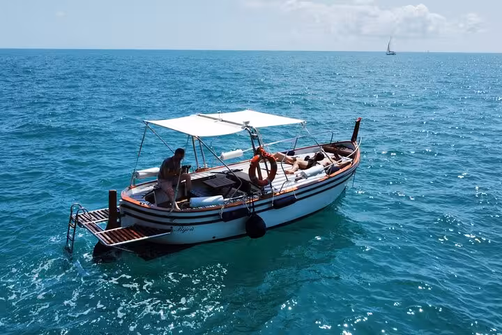 Side view of a boat with a canopy and passengers enjoying the serene waters on the La Spezia boat tour.