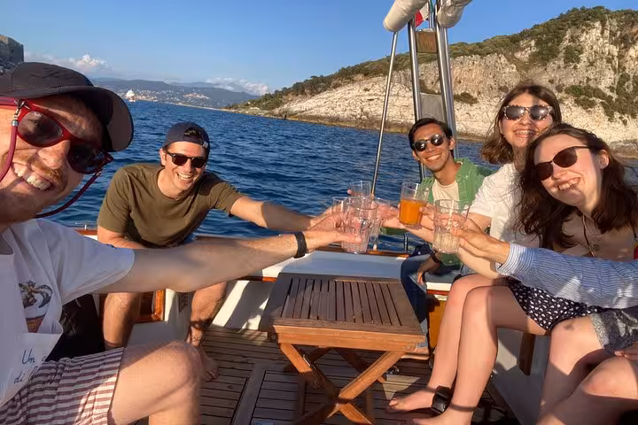 Happy tourists toasting drinks on a boat with scenic coastal views during the La Spezia Portovenere tour.