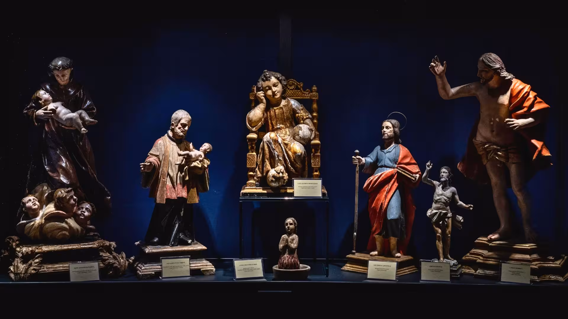 Collection of religious statues in a Laconi museum exhibit, highlighting Sardinian art and history on a guided tour.