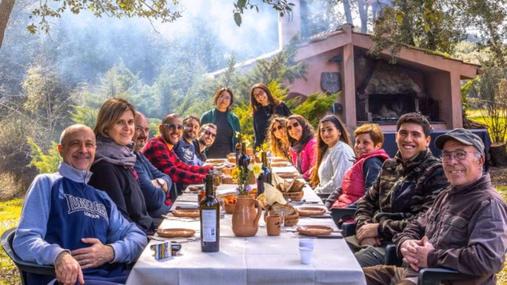Smiling group enjoying outdoor lunch after a truffle hunting excursion in the serene Laconi countryside.