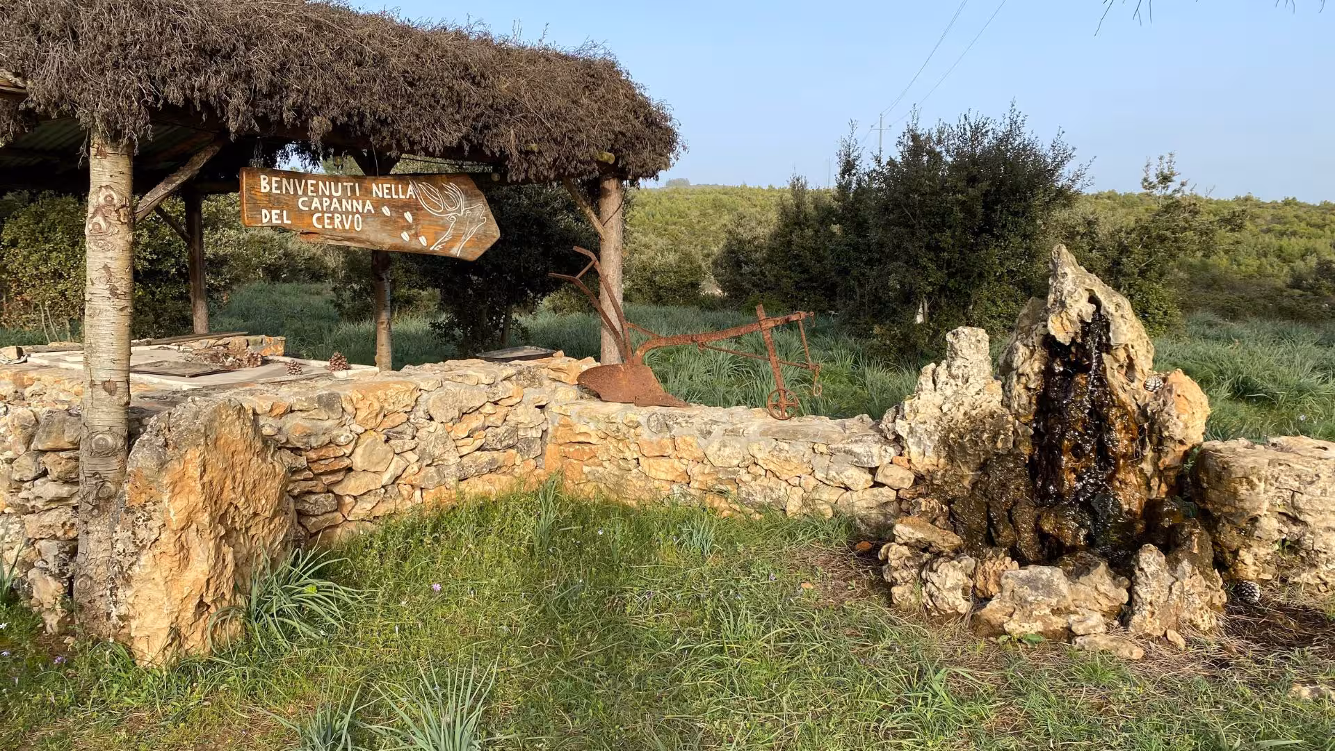 Rustic stone structure and wooden sign in Laconi's scenic truffle hunting area, ideal for outdoor adventures.