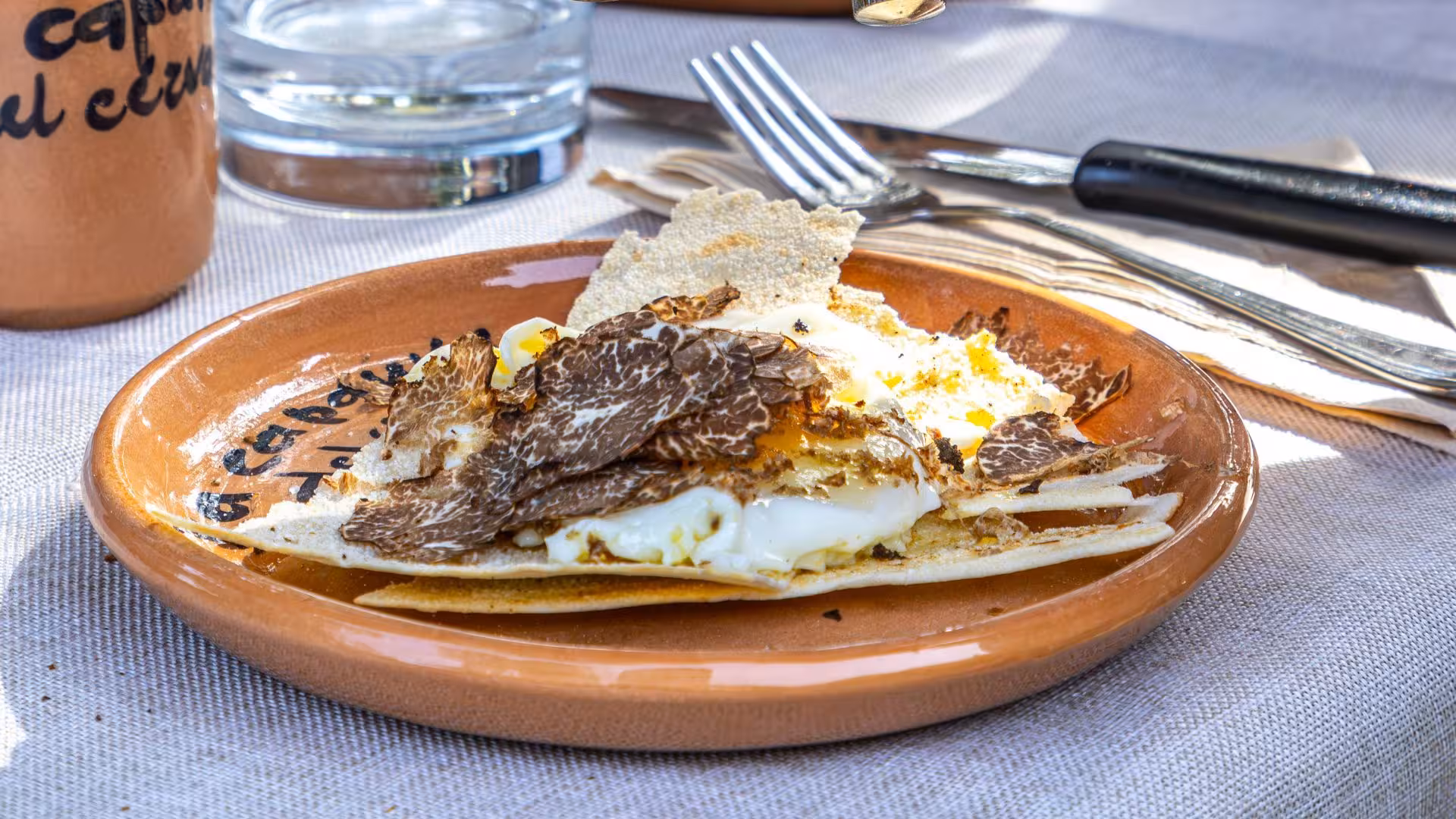 Savory dish with shaved truffles on a rustic plate, showcasing culinary delights of Laconi truffle hunting excursion.