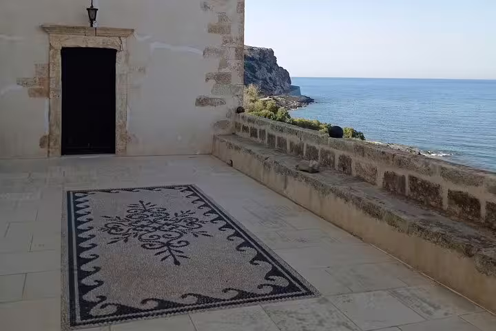 Peaceful stone courtyard of Lady of the Angels Monastery overlooks serene sea views, enhancing the spiritual ambiance.