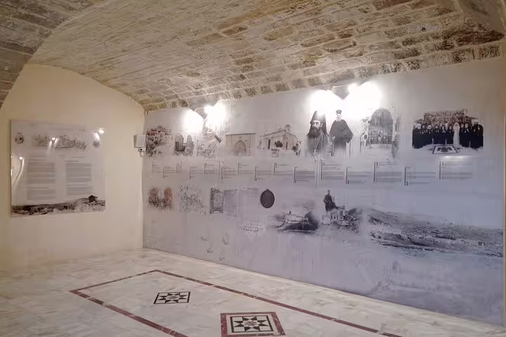 Historical display wall inside Lady of the Angels Monastery with sepia images and text under arched stone ceiling.