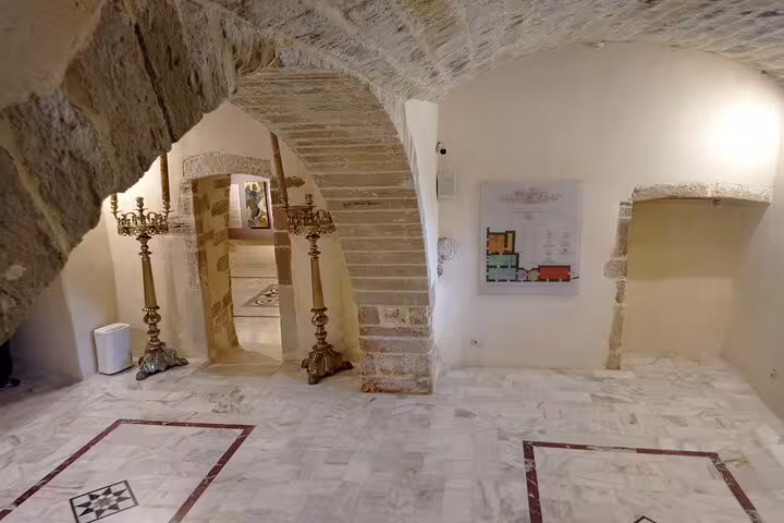 Stone-arched hallway in Lady of the Angels Monastery featuring intricate floor patterns and wall decor.