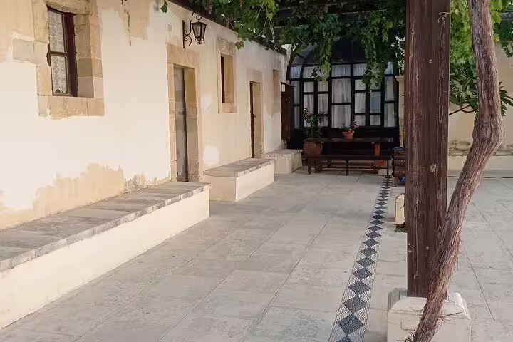Serene walkway at Lady of the Angels Monastery featuring stone benches and vine-covered pergola for tranquil reflection.