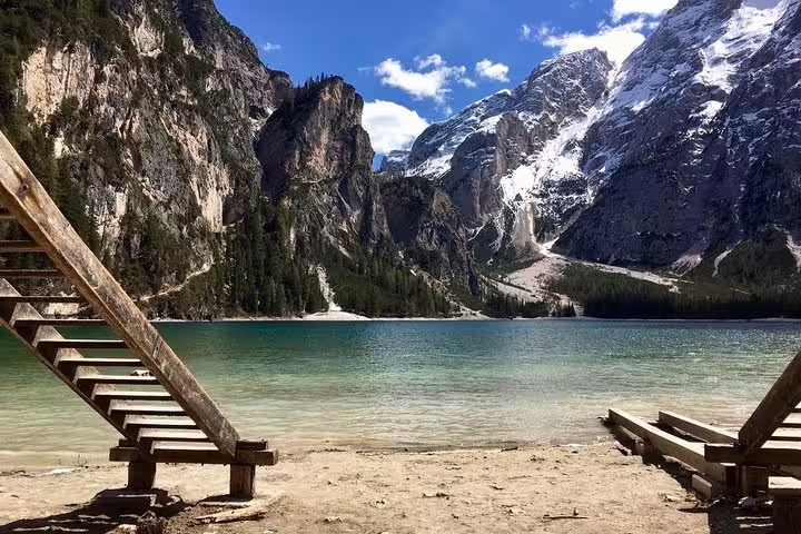 Scenic view of Lago di Braies with crystal-clear water and snow-capped Dolomites in the background.