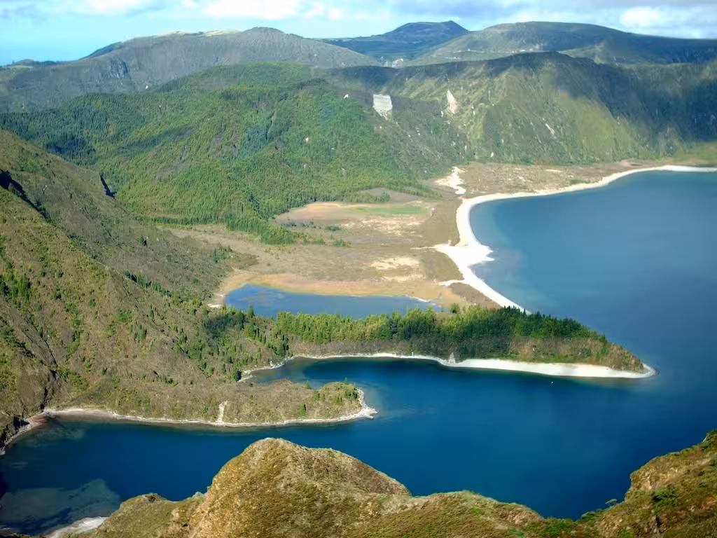 Panoramic view of Lagoa do Fogo crater lake in São Miguel, Azores, with turquoise water, white sand beach and lush green hills