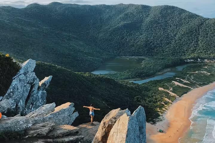 Hiker enjoys panoramic views of Lagoinha do Leste beach and lush hills, captured on a scenic photography tour.