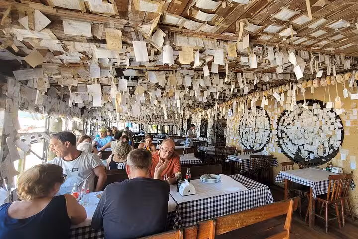Cozy restaurant interior at Lagoinha do Leste with tables and walls adorned with hundreds of hanging notes.