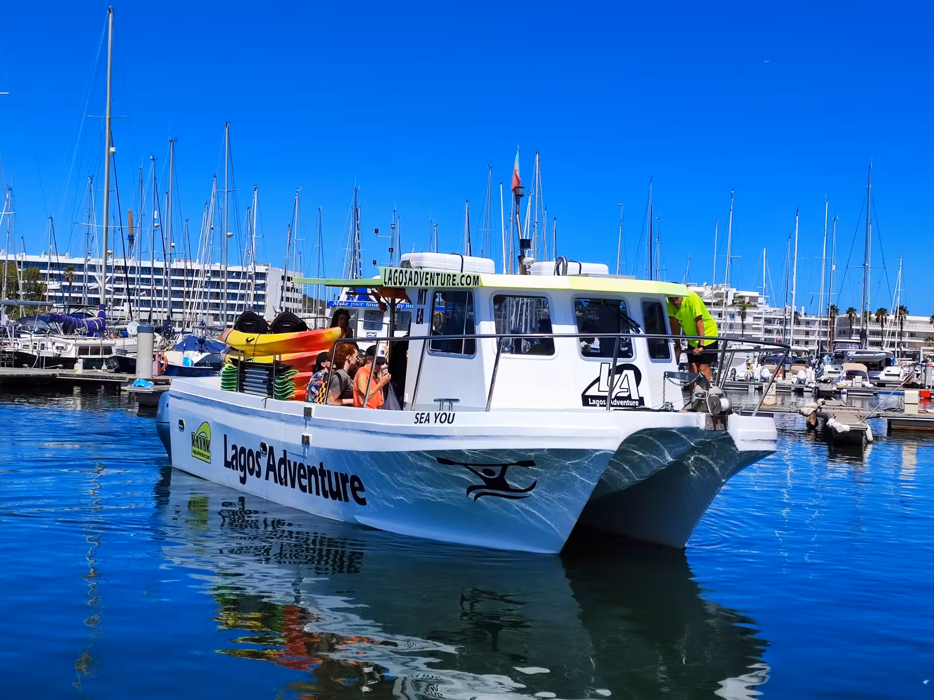 Lagos Adventure catamaran loaded with colorful kayaks departs Lagos Marina for guided Algarve sea cave tour