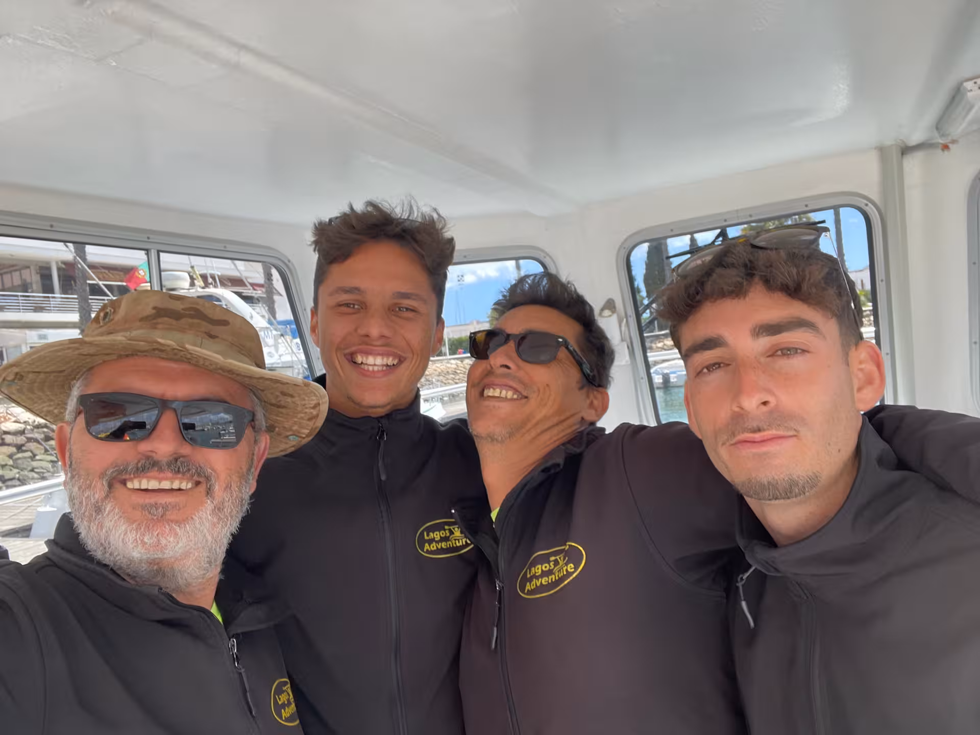 Smiling Lagos Adventure kayak guides in branded jackets welcome guests aboard boat at Lagos Marina in the Algarve