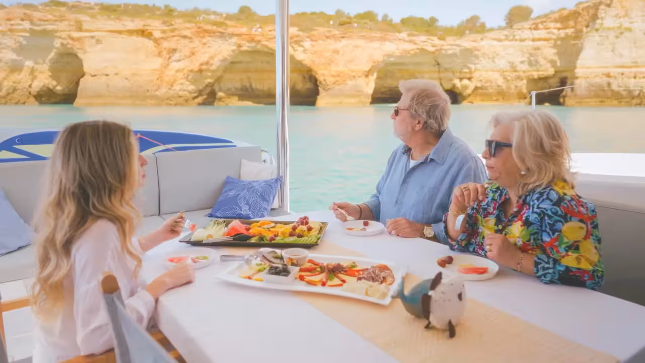 Guests enjoying a scenic brunch on a luxury yacht near Ponta da Piedade golden limestone cliffs in Lagos.