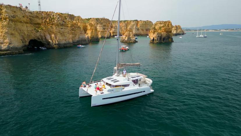 White catamaran sailing by Ponta da Piedade cliffs in Lagos on a full-day Algarve cruise with sea caves