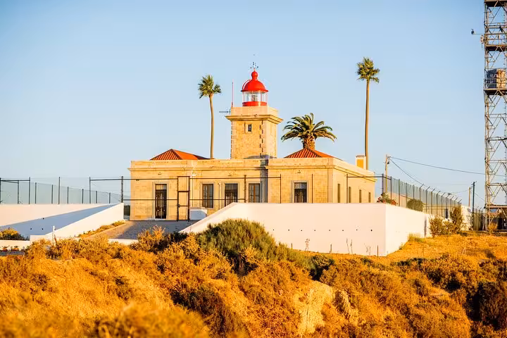 Historic lighthouse with red dome on a sunny hilltop in Lagos, ideal for sightseeing during a city walk.