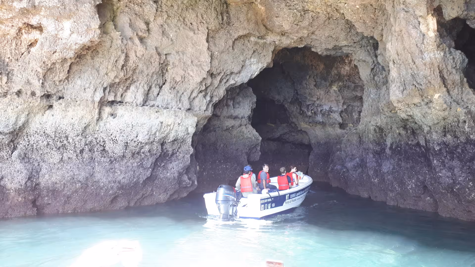 Guided Lagos boat tour approaches a vast rock arch at Ponta da Piedade, exploring Algarve sea caves and crystal-clear waters