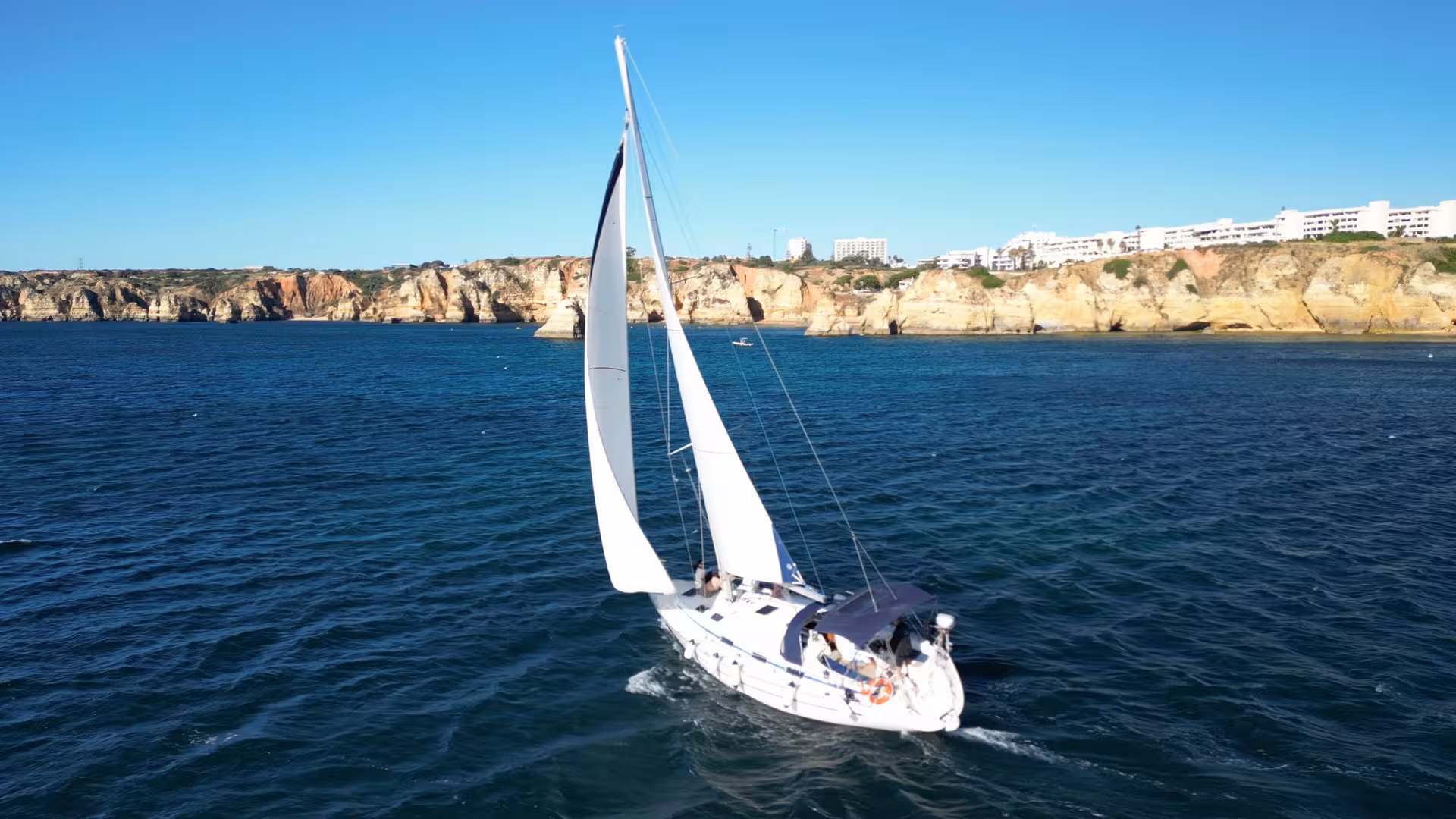 Sailing yacht cruising off Lagos Algarve cliffs on a full-day yacht cruise adventure with ocean views