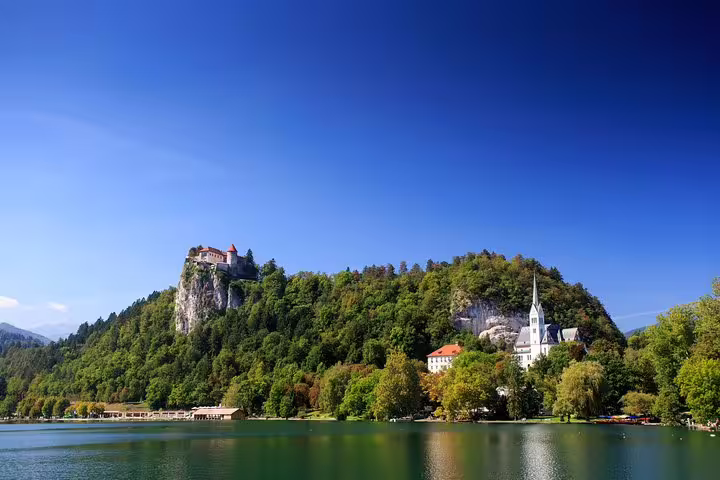 Scenic Lake Bled summer tour with Bled Castle on the cliff and lakeside church reflected in calm water