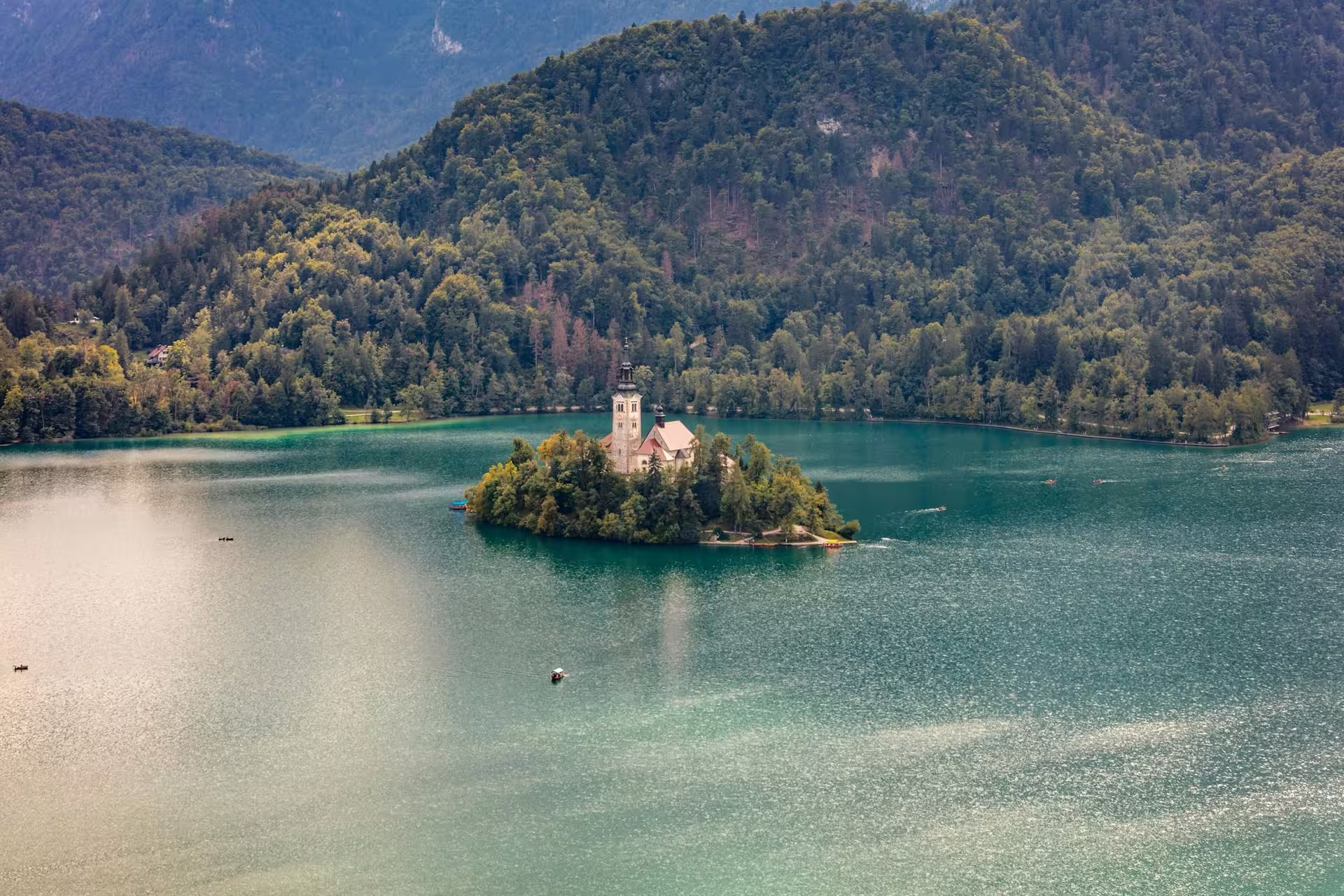 Aerial view of Lake Bled island church on a summer tour, with turquoise water and forested hills