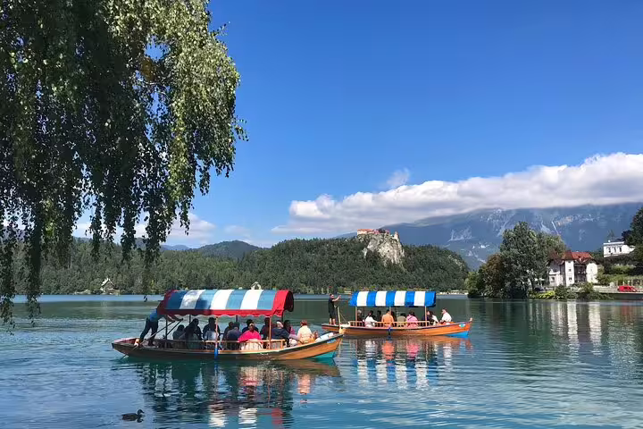 Traditional pletna boat ride on Lake Bled in summer with views toward Bled Castle and Alps