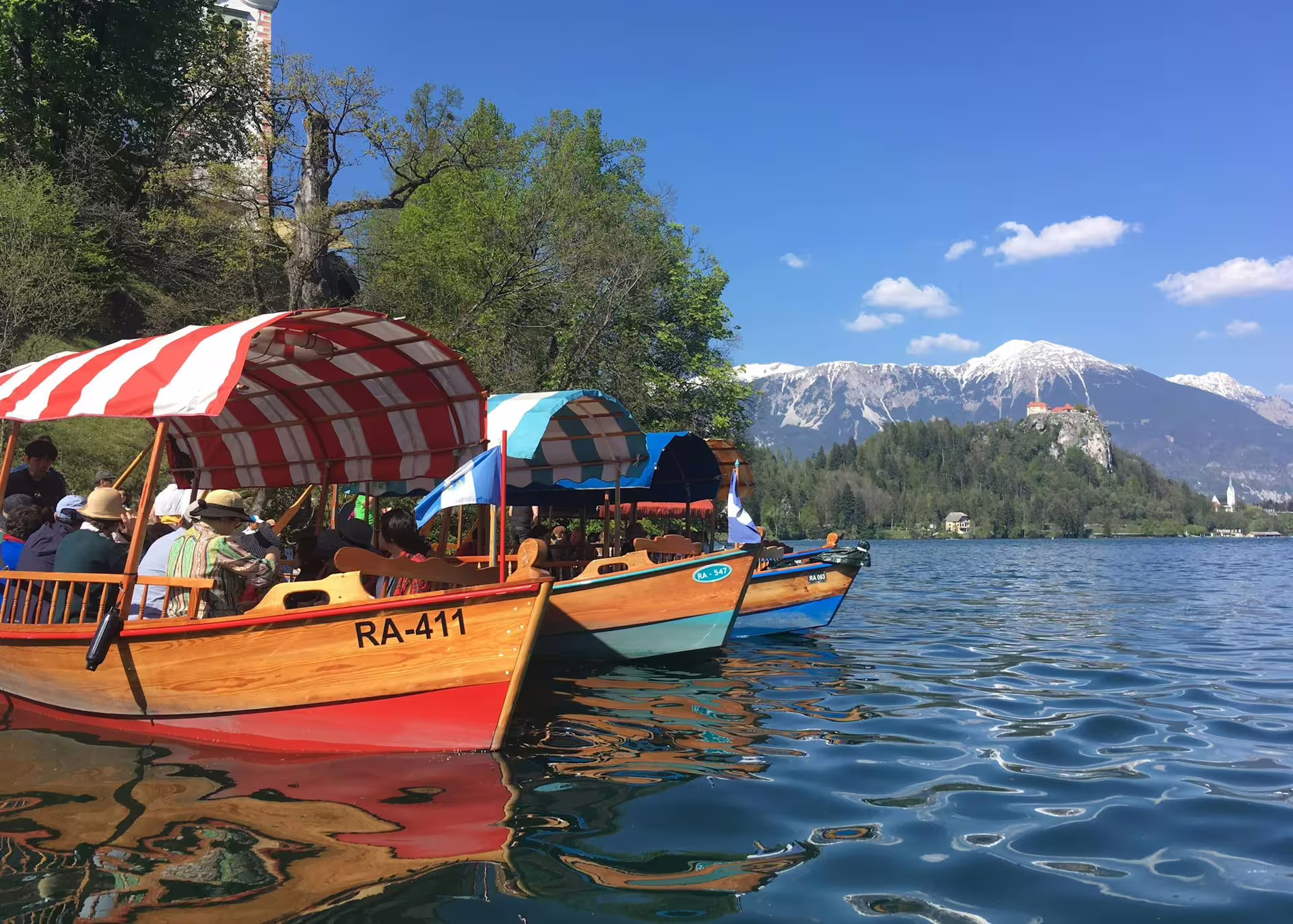 Traditional pletna boats on Lake Bled with alpine views, included boat ride on the summer Lake Bled tour