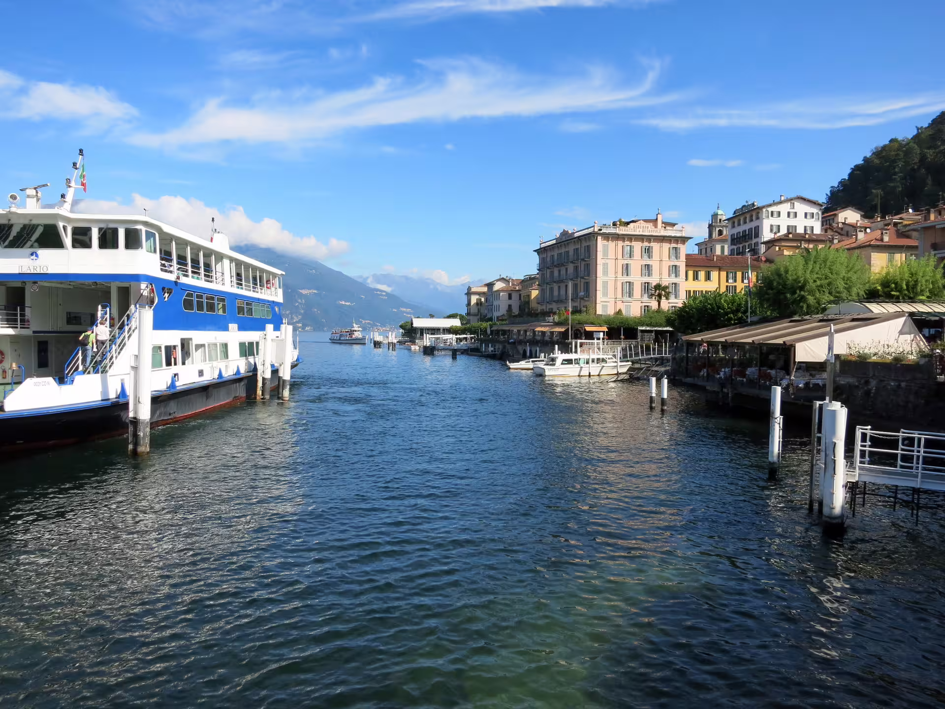 Lake Como ferry arriving at Bellagio waterfront, colorful villas and Alps backdrop on Milan to Como Lake tour