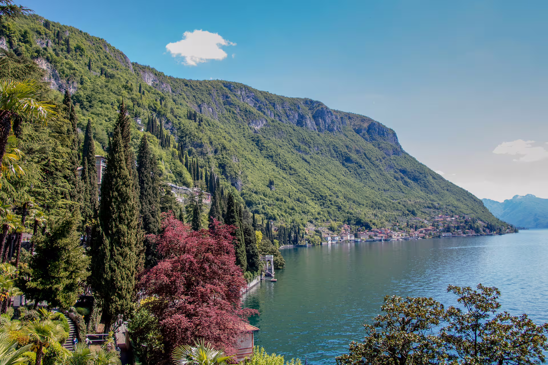 Scenic Lake Como shoreline with lush green mountains, villas and gardens viewed on a relaxing 2 hour walking tour