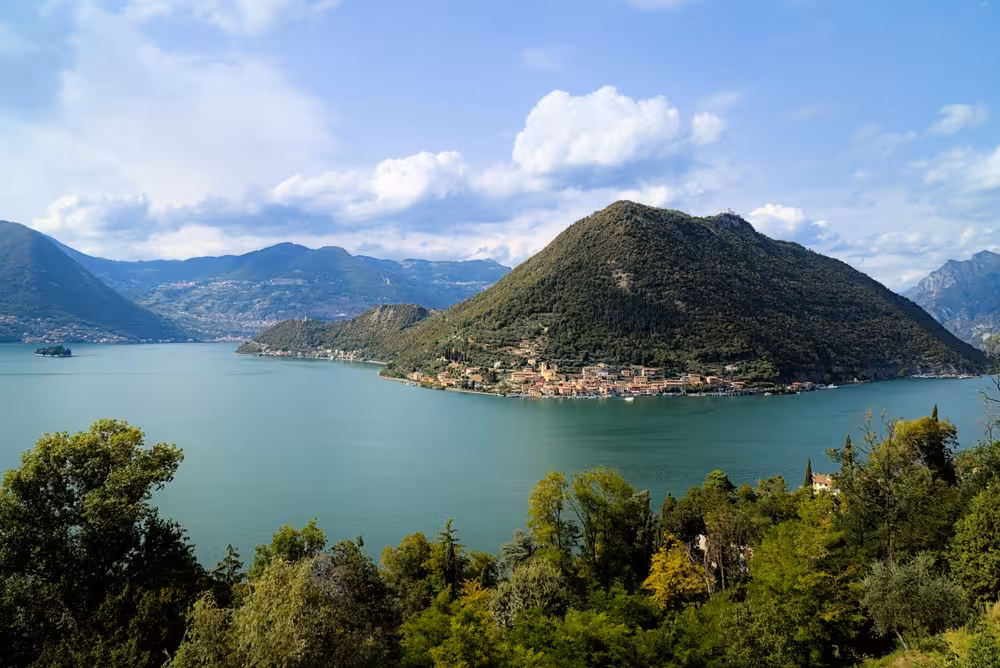 Scenic view of Lake Iseo with lush hills and quaint villages, perfect for a tranquil Franciacorta cruise escape.