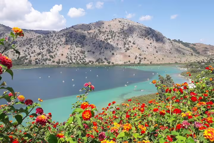 Scenic view of Lake Kournas with vibrant flowers and mountains on the Chania private tour from Rethymno.