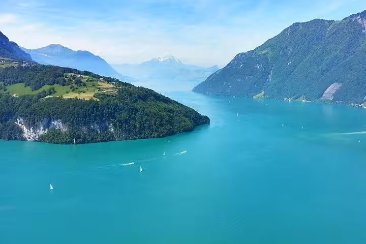 Aerial view of turquoise Lake Lucerne surrounded by lush greenery and the majestic Swiss Alps.