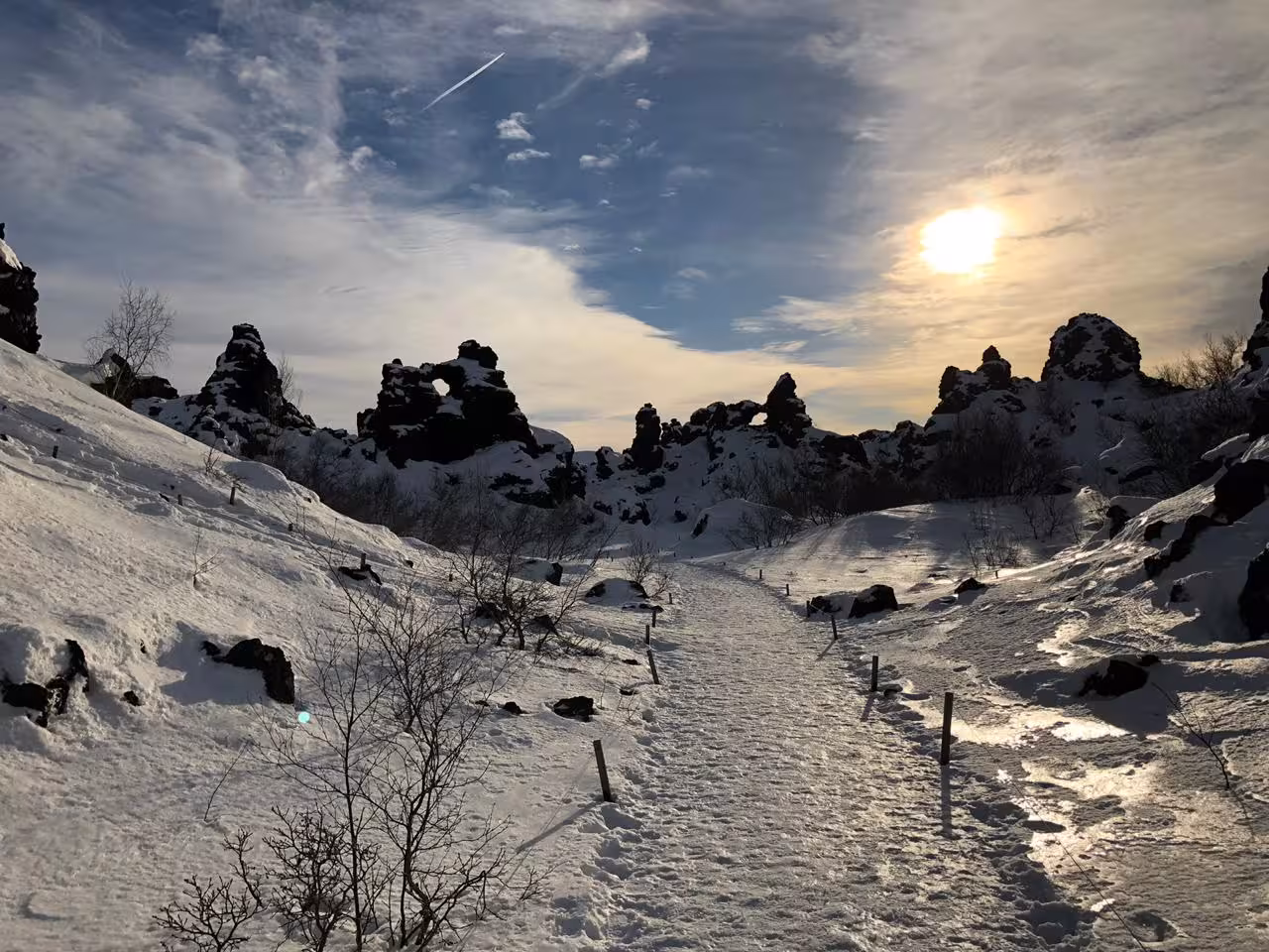 Snowy path through Dimmuborgir rock formations at Lake Myvatn under a bright sun, ideal for winter tours.