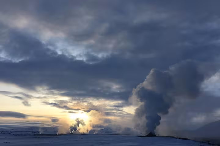 Steaming geothermal activity under a dramatic sky at Lake Myvatn in Iceland, showcasing nature's raw beauty and power.