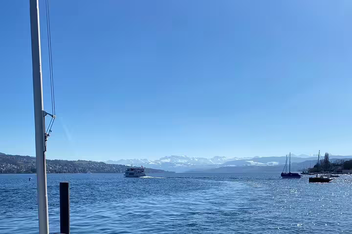 Scenic view of a boat cruising on the serene Lake of Zurich with snow-capped mountains in the background.
