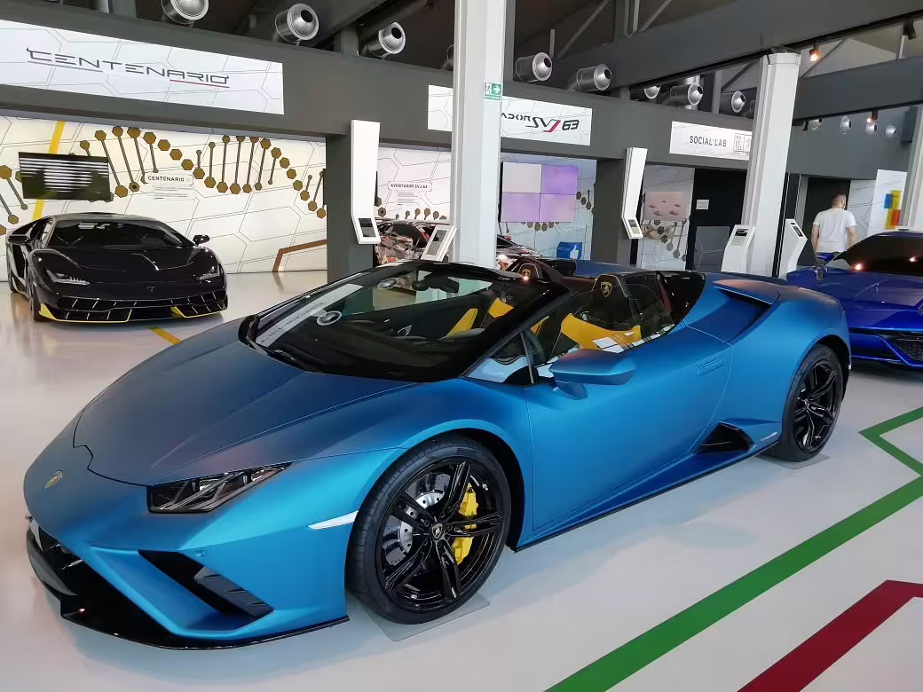 Vibrant blue Lamborghini convertible and Centenario model featured in the Lamborghini Museum, perfect for factory tour enthusiasts.